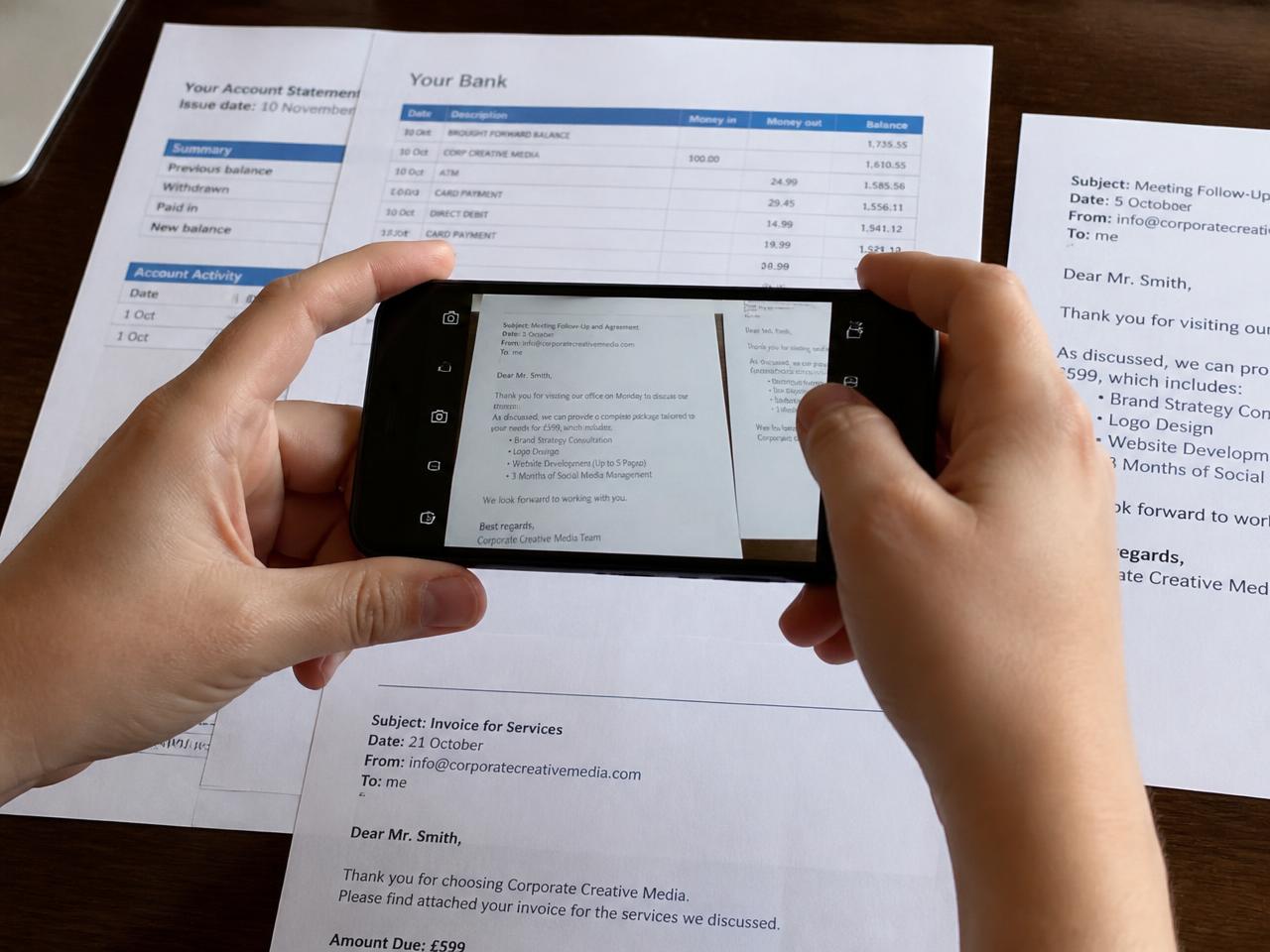 Persona che fotografa con lo smartphone estratti conto ed email stampate per conservare le prove di una truffa
